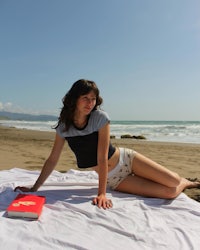 a girl laying on a blanket on the beach