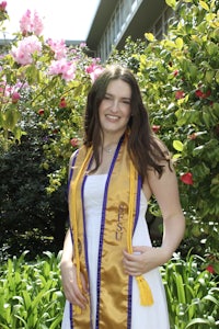 a woman in a white dress with a gold sash