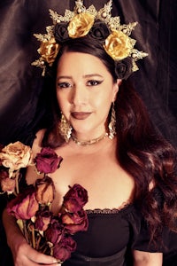 a woman in a black dress with a gold crown and roses