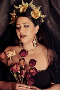 a woman in black and gold holding roses