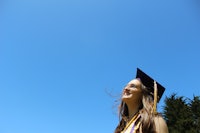 a woman in a graduation gown is looking up at the sky